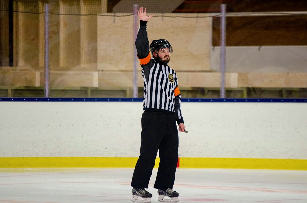 Robert Dahlberg dömer en ishockeymatch, med armen uppe för fördröjd utvisning.